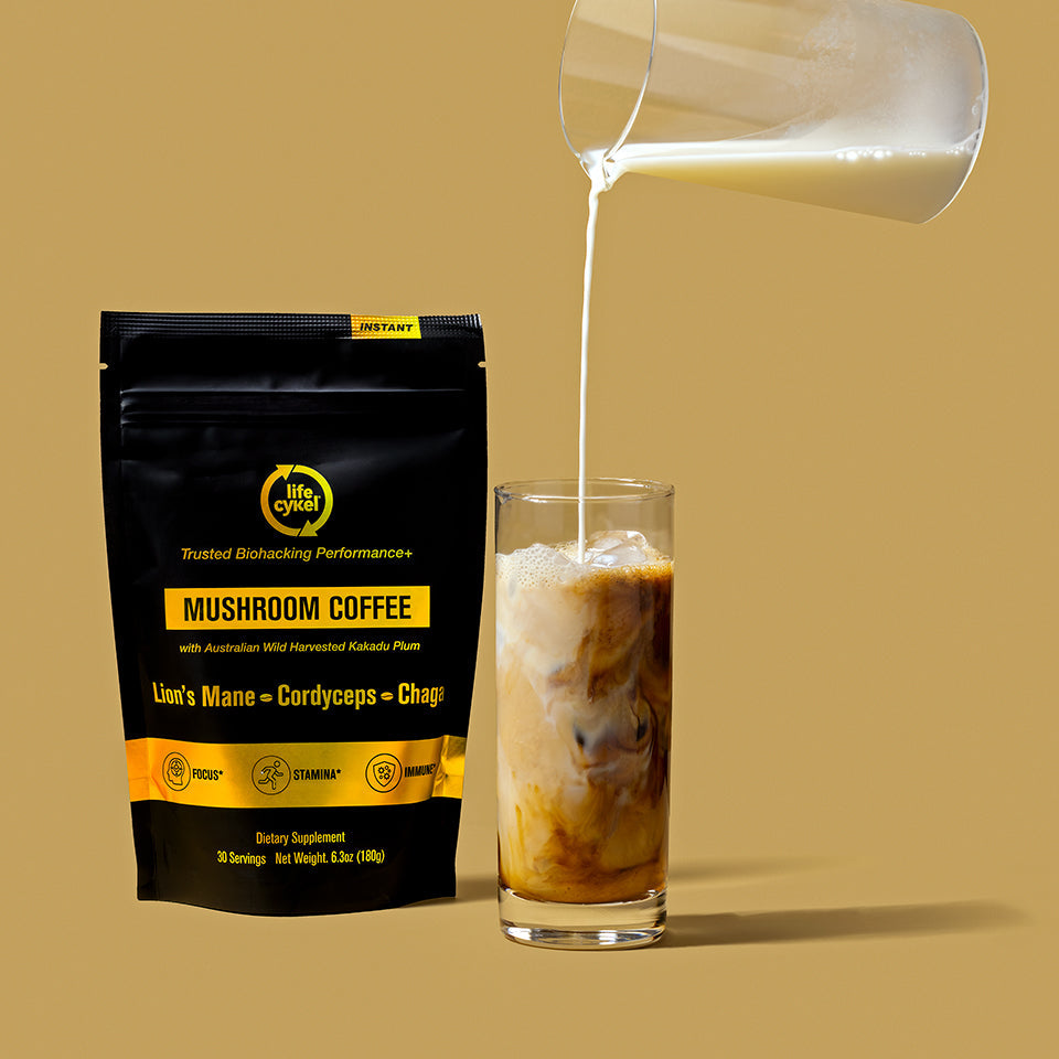 Lifecykel mushroom coffee pouch with milk poured to a glass cup on the side in plain yellow background