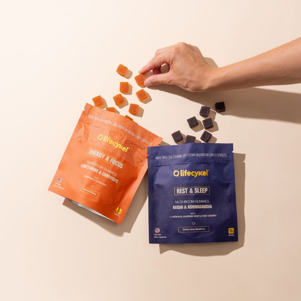 Hand picking a supplement from a 'lifecykel' package on a beige background