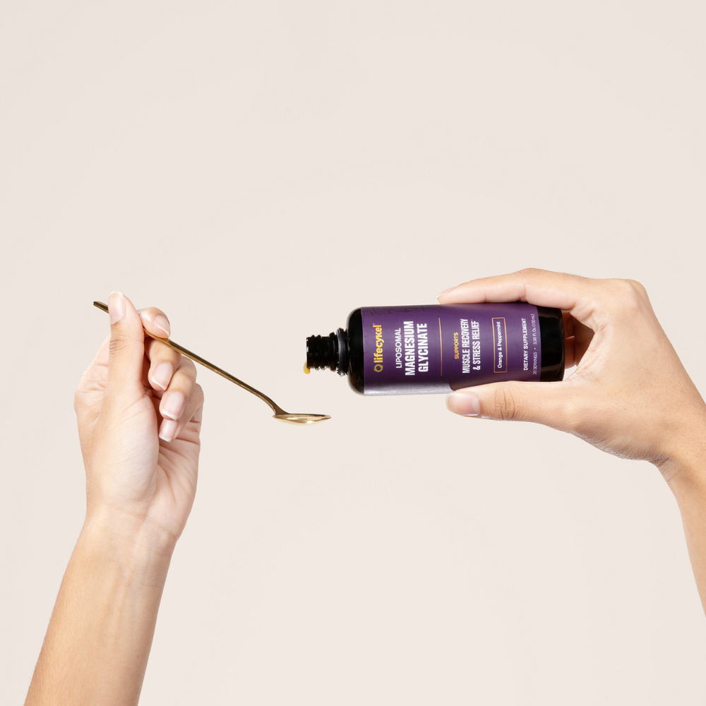 Hand holding a purple bottle with a dropper over a beige background