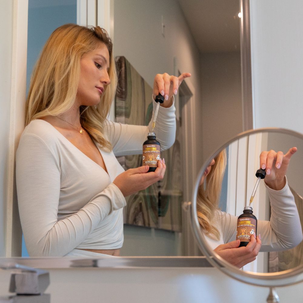 Woman with Lifecykel Shiitake mushroom extracts supplements product bottle with dropper in front of a mirror