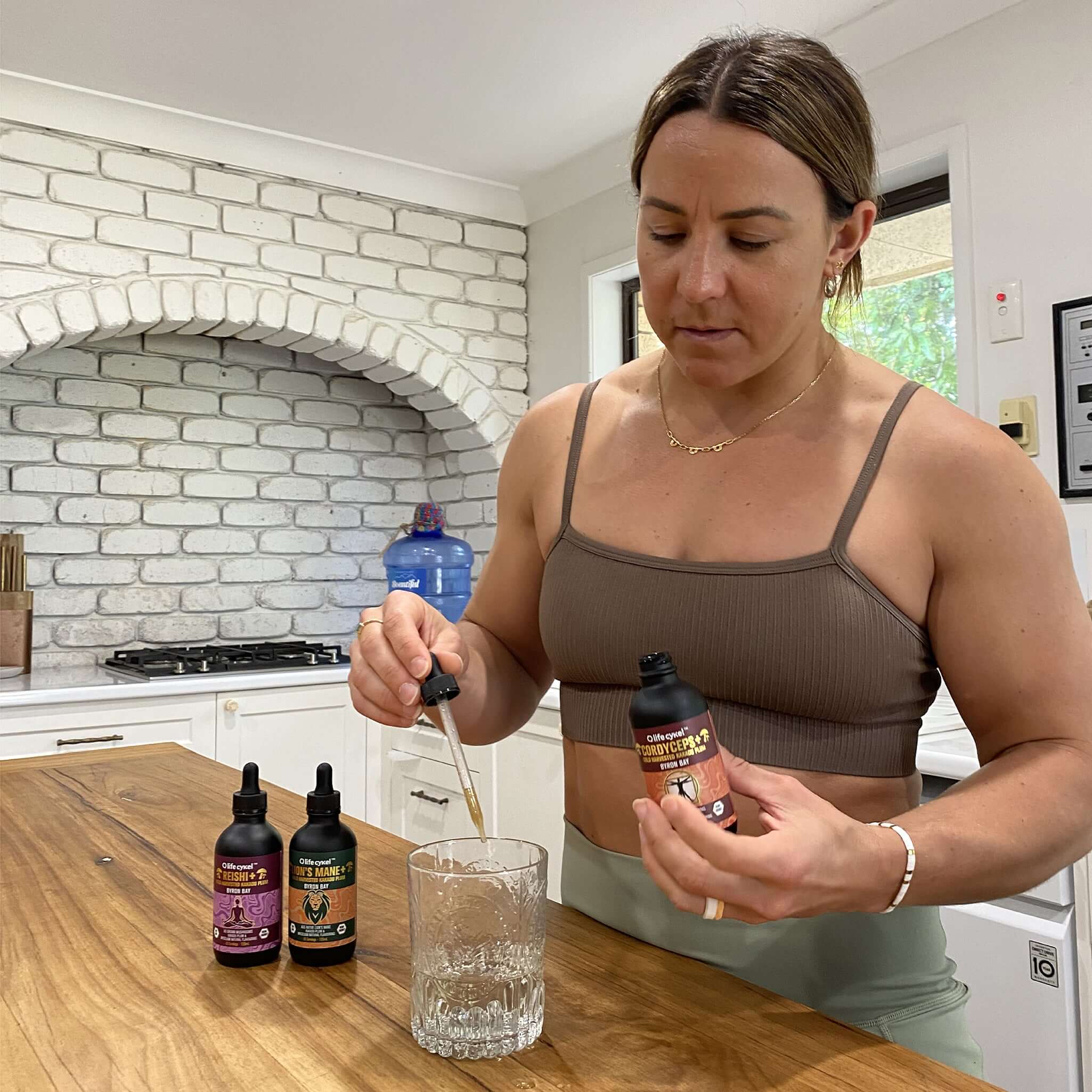 Woman pouring Lifecykel Chaga mushroom extracts supplement liquid to glass cup