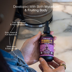 Hand holding a bottle of Lifecykel Reishi mushroom extract supplement with text highlighting features, against a blurred kitchen background.
