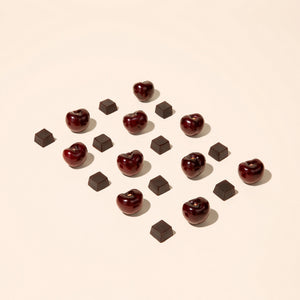 Cherries and gummy cubes pieces arranged in a pattern on a beige background