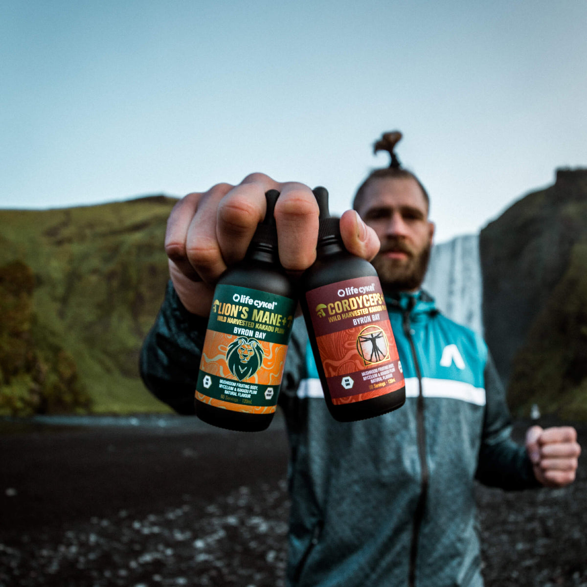 Man holding two bottles of Lifecykel mushroom extracts supplements with waterfalls on the background